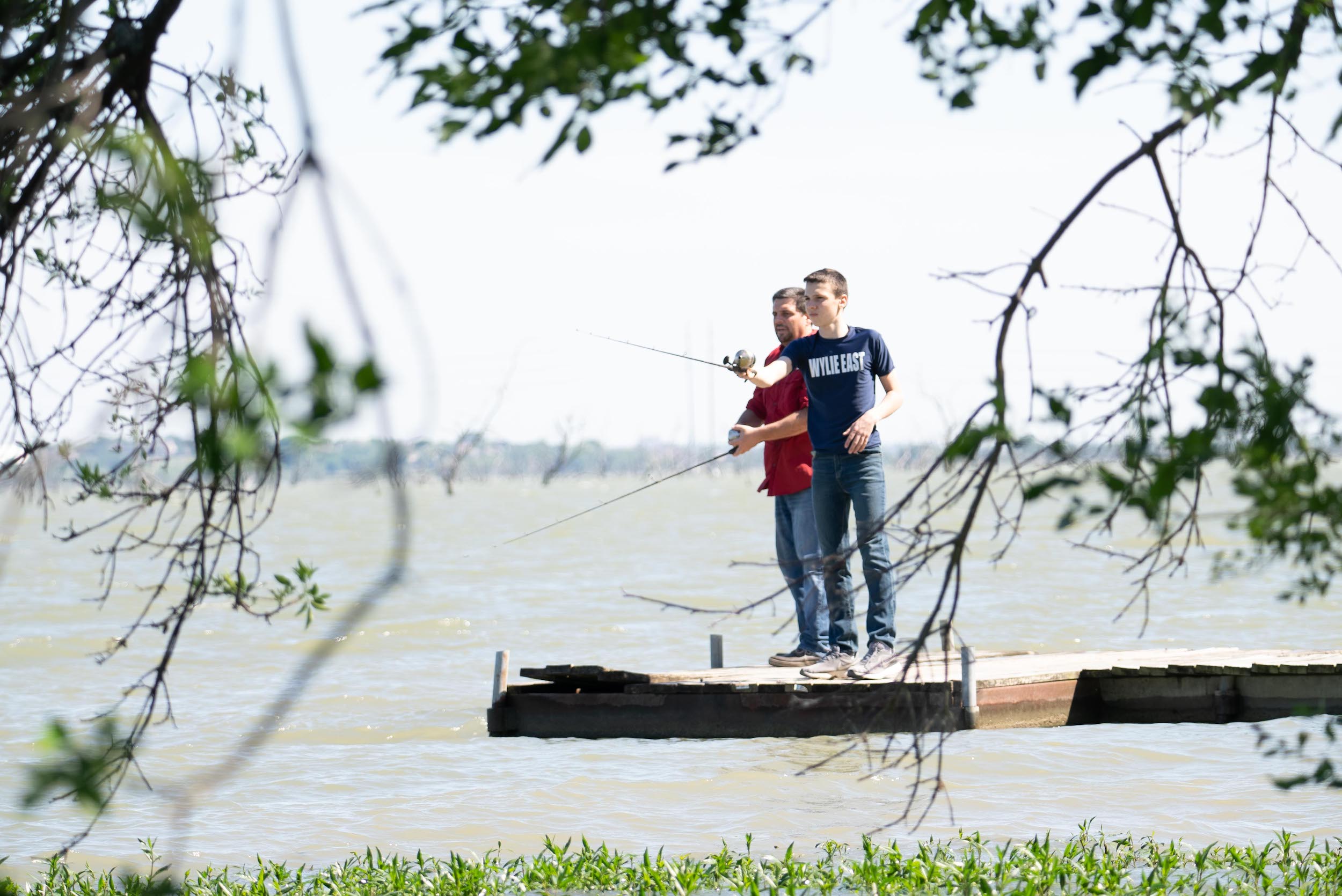 A boy and his father fishing off of a dock